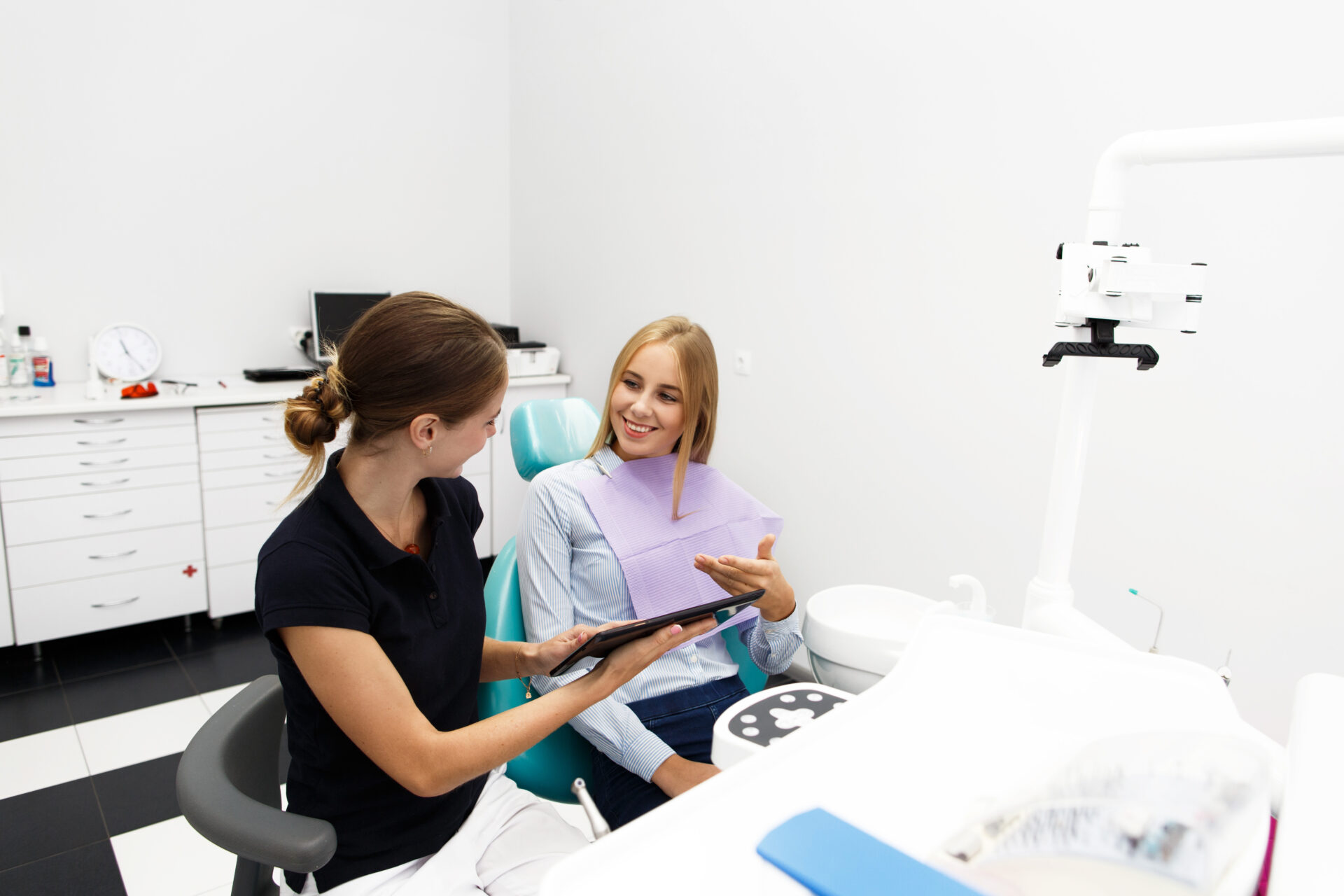 smiling woman sits chair dentist office while doctor shows her something
